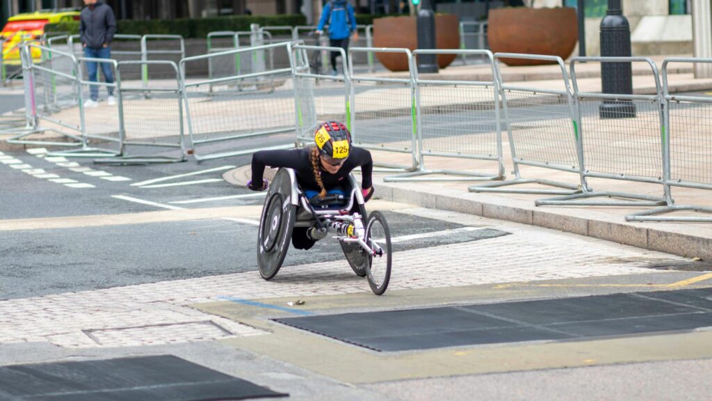 A dedicated athlete competes in a marathon using a racing wheelchair on city streets.